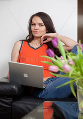 Bonn  Deutschland  Frau mit Laptop auf dem Sofa