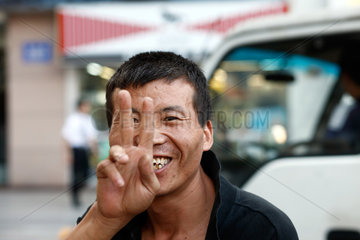 Shenzhen  China  junger Mann zeigt das Victory-Zeichen in die Kamera