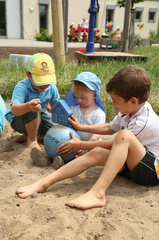 Saarbruecken  Deutschland  drei Jungs spielen im Sand einer Kindertagesstaette