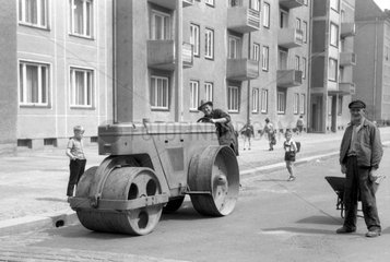 Berlin  DDR  Bauarbeiter planiert auf einer Walze eine Strasse