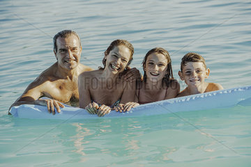 Family swimming with inflatable in swimming pool