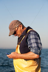Kussfeld  Polen  kaschubischer Fischer schreibt eine SMS