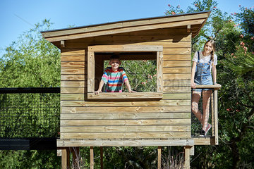Boy and teenage girl standing in a log cabin