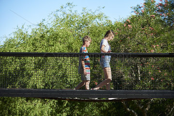 Brother and sister walking on footbridge