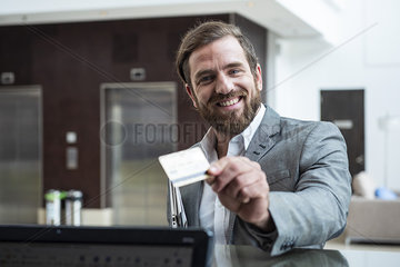 Businessman standing with credit card at hotel reception counter