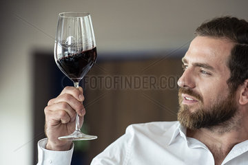 Mid adult man looking at wine glass
