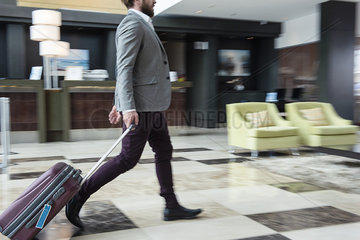 Businessman walking with wheeled luggage
