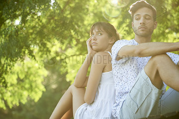 Angry young couple sitting in park