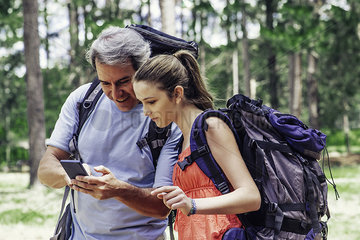Father and daughter using smart phone in forest