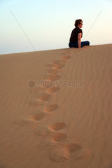 Abu Dhabi  Vereinigte Arabische Emirate  eine Frau in der Wueste bei Sonnenuntergang