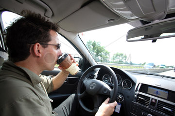 Hamburg  Deutschland  Mann trinkt Kaffee beim Autofahren