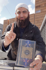 Berlin  Deutschland  Mann zeigt mit erhobenem Zeigefinger den Koran