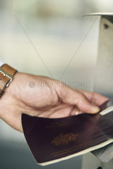 Human hand inserting passport in machine