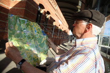 Luebbenau  Deutschland  aelterer Mann schaut sich eine Landkarte an