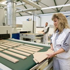Mengen  Deutschland  Mitarbeiterin einer Moebelfabrik legt Holzplatten auf ein Fliessband
