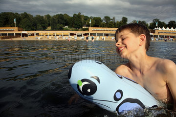 Berlin  Deutschland  ein Junge schwimmt lachend mit seinem Gummitier im Wasser