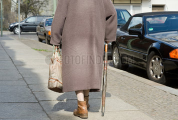 Berlin  Deutschland  alte Frau mit Stock und Beutel auf dem Gehweg