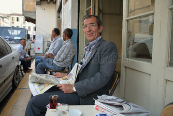Nikosia  Tuerkische Republik Nordzypern  Mann liest Zeitung in einem Strassencafe