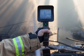 Berlin  Deutschland  Feuerwehrmann sucht nach Glutnestern mit einer Waermebildkamera