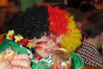 Berlin  Deutschland  Junge mit Peruecke und Gesichtsbemalung in den deutschen Nationalfarben schlaeft