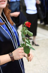 Bremen  Deutschland  eine Absolventin haelt eine rote Rose in der Hand