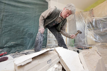 Berlin  Deutschland  Handwerker zerschlaegt Mauersteine mit einem Hammer