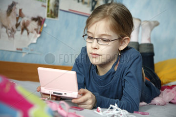 Hamburg  Deutschland  ein Maedchen spielt in ihrem Kinderzimmer Nintendo DS