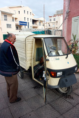 Oristano  Italien  Mann steht vor seinem dreiraedrigen Lieferwagen