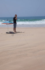 Mann mit Sonnenschirm am Strand