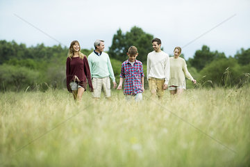 Family walking together in field of tall grass