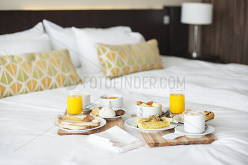 Breakfast trays on bed in luxury hotel room
