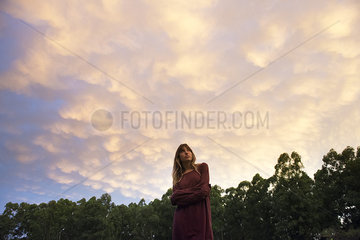 Young woman outdoors at twilight  looking up in thought