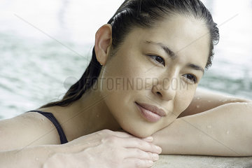 Woman at side of swimming pool resting head on arms