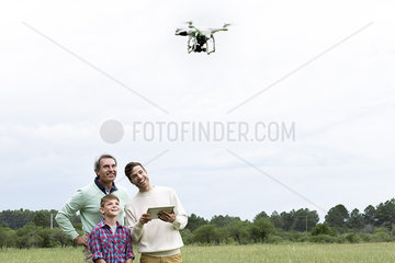 Family using digital tablet to control drone outdoors