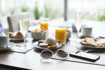 Sunglasses and breakfast on table in cafe