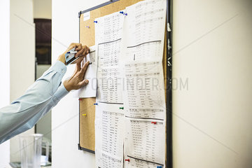 Woman pinning document on office bulletin board