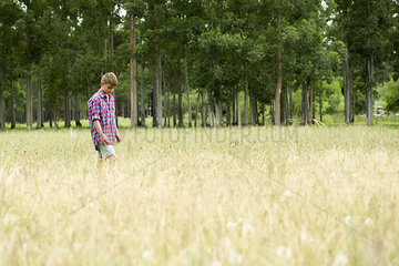 Boy walking alone through field