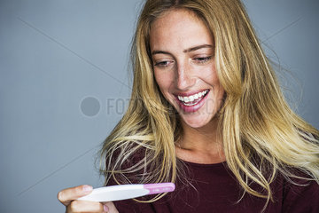 Young woman looking at pregnancy test and smiling