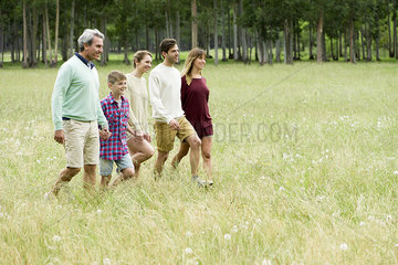 Family taking walk together through field