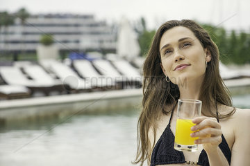 Woman drinking juice next to swimming pool