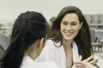 Women in bathrobes chatting outdoors