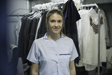 Young woman with clothes racks in foreground  portrait