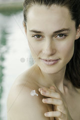 Woman applying moisturizer to shoulder
