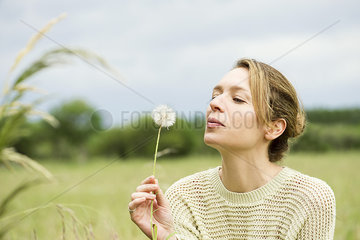 Woman blowing dried dandelion flower