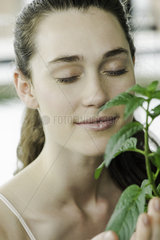 Young woman smelling plant