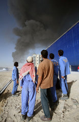 Dubai  Vereinigte Arabische Emirate  Maenner blicken auf eine schwarze Rauchwolke