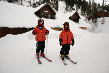 Krippenbrunn  Oesterreich  Kinder auf Skiern vor einer eingeschneiten Huette