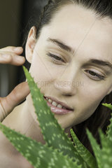 Young woman toucing aloe vera plant