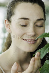 Young woman smelling plant