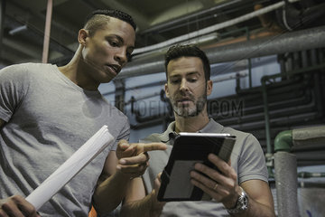 Men working in industrial setting using digital tablet